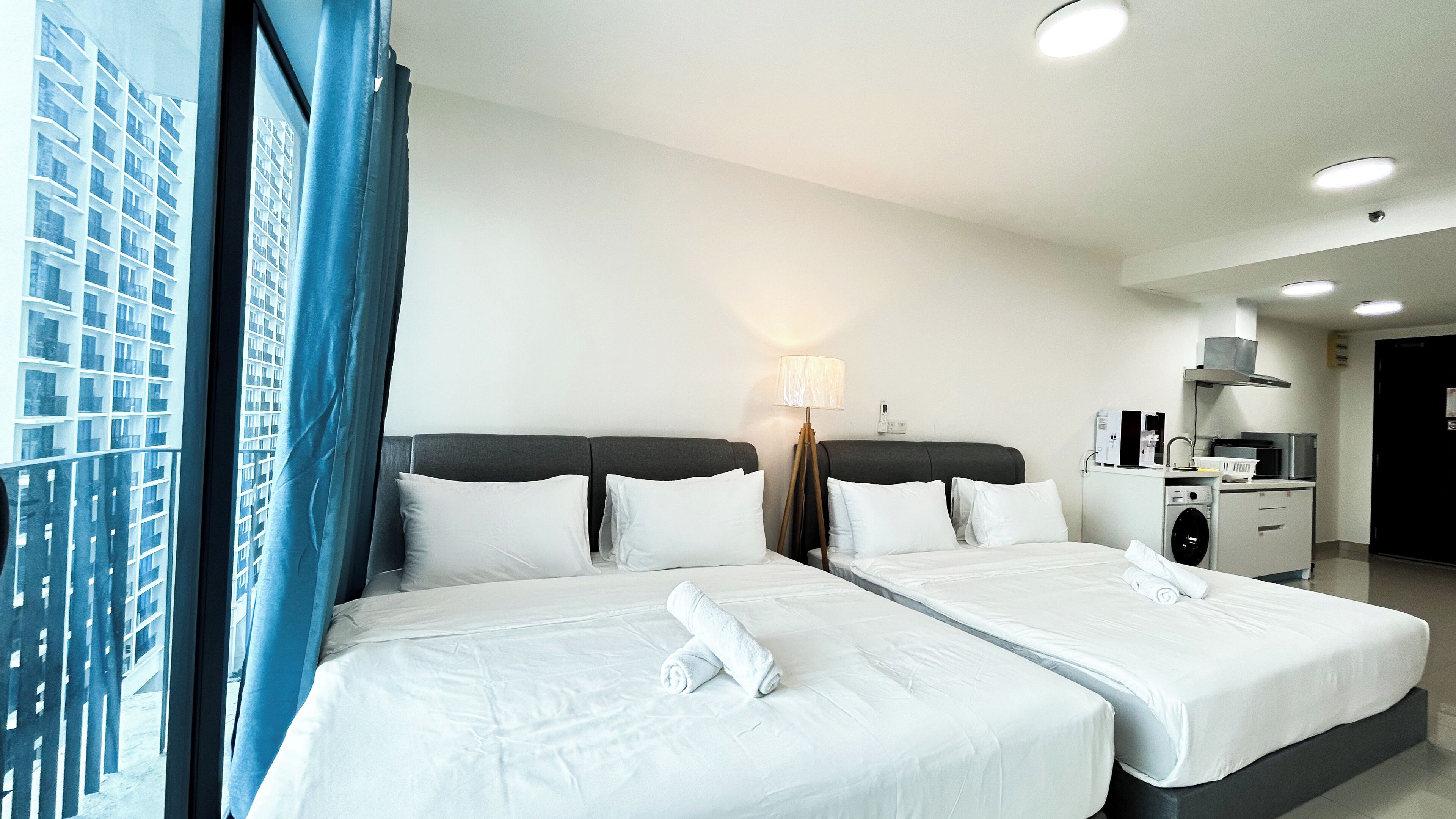 Habitación de hotel con dos camas, lavadora y kitchenette.