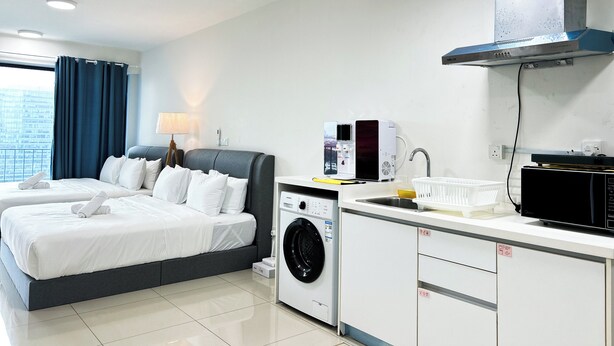 A hotel room with a bed, a washing machine, a microwave, and a sink. - Trefoil by Manhattan Group  (Shah Alam)