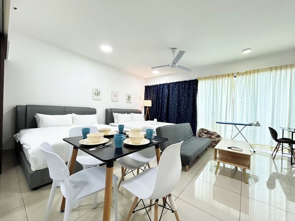 Una habitación de hotel con cama, una mesa de comedor con sillas, un sofá, una mesita con una silla y un ventilador de techo.