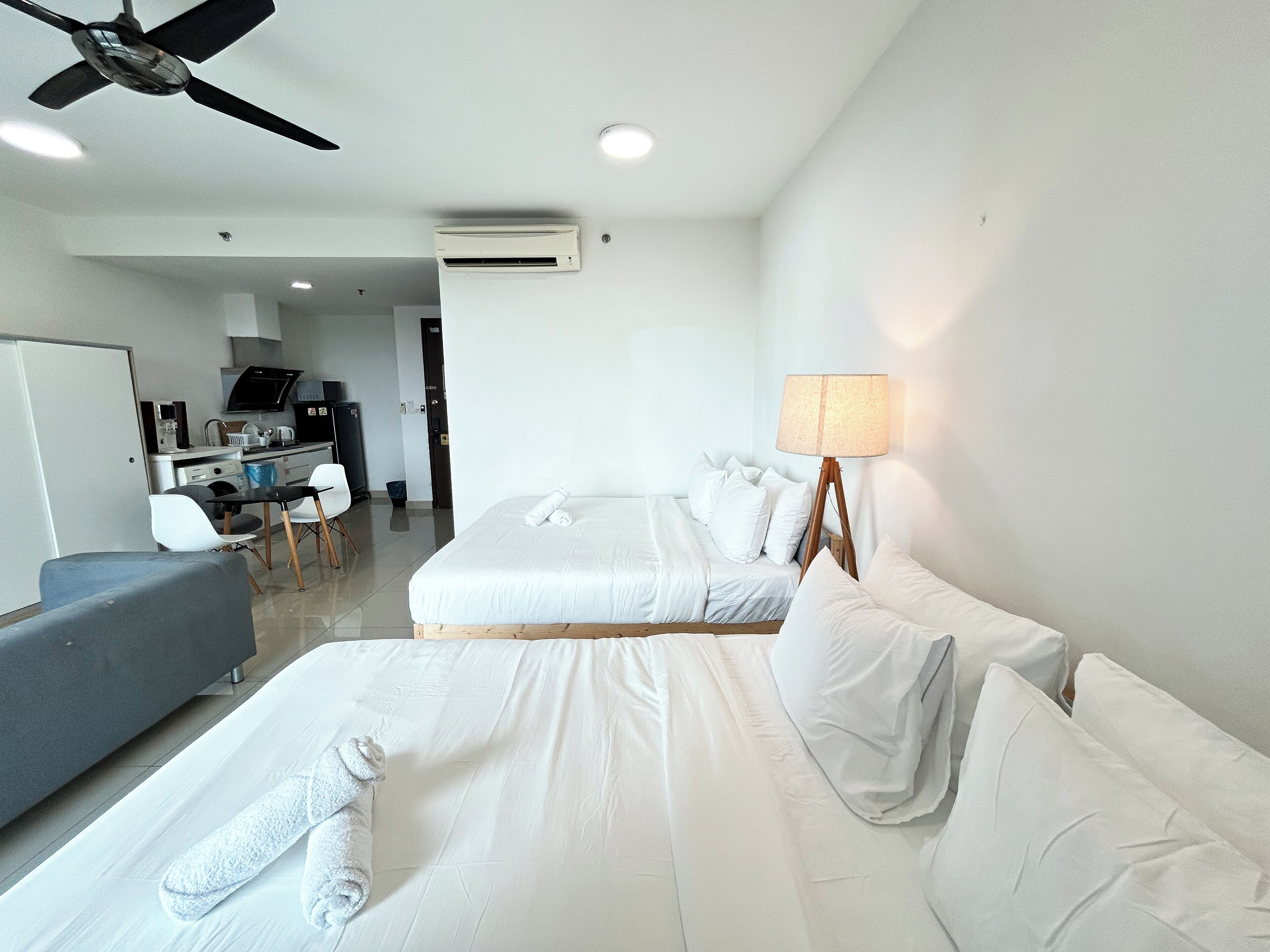 A hotel room with two beds, a desk, a chair, and a ceiling fan.