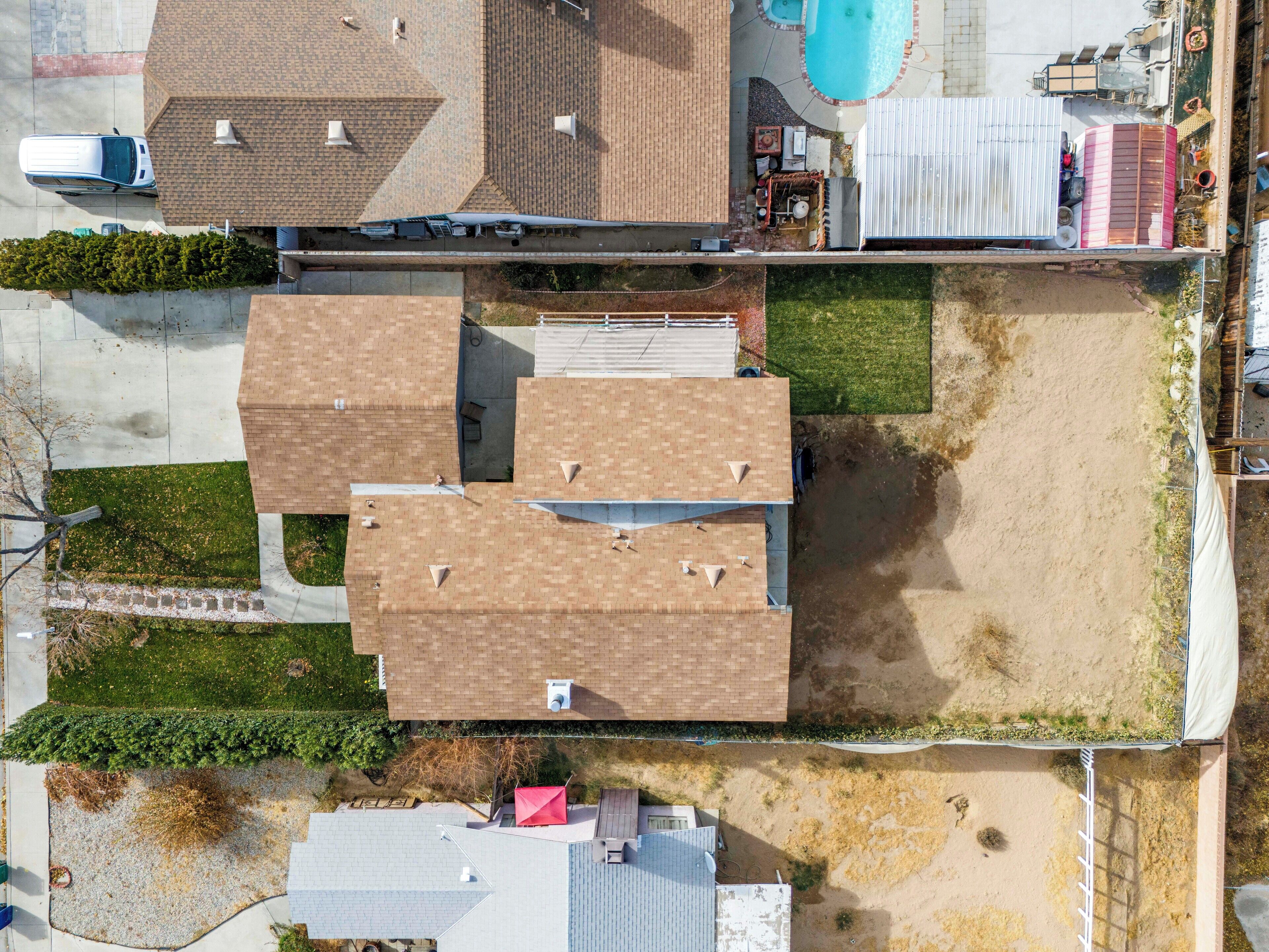 An aerial view of a residential area with multiple houses, a swimming pool, and a fenced yard.