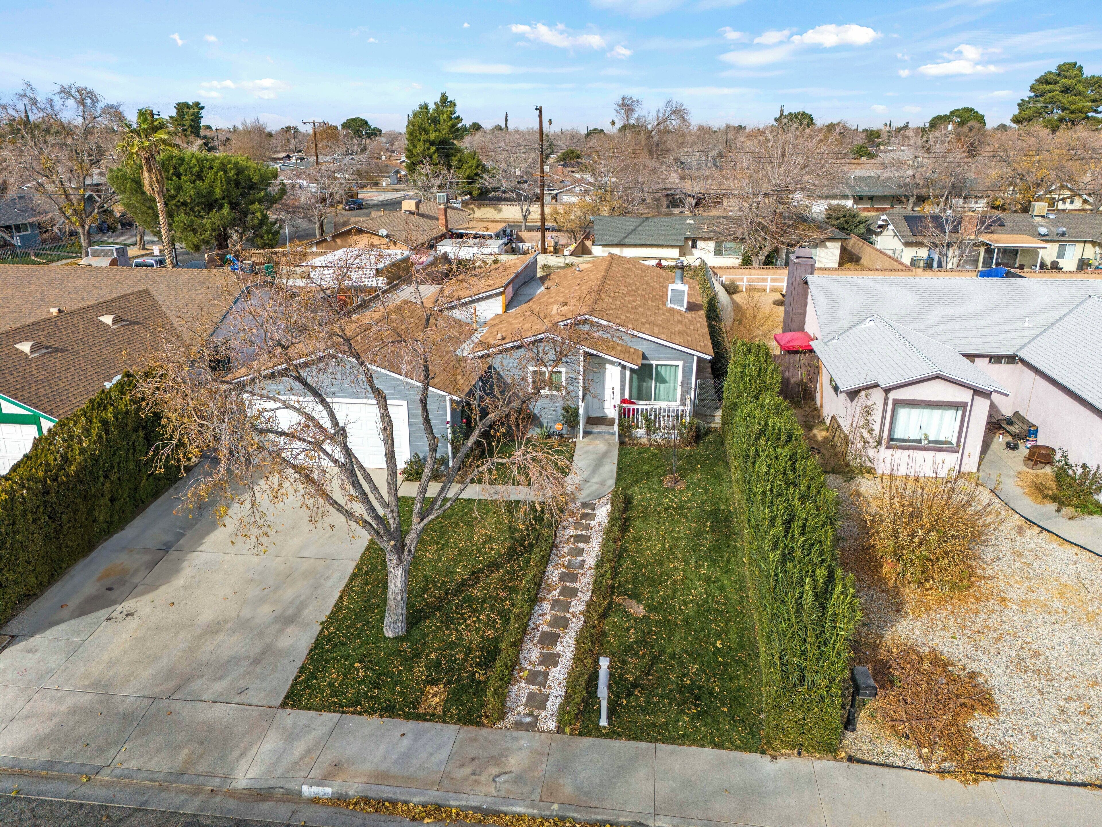 A residential area with houses, a clear sky, and a well-maintained lawn.