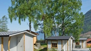 A row of small, single-story cabins with a gravel driveway and wooden benches. - 4 Person Holiday Park Home in Kinsarvik (Ullensvang)