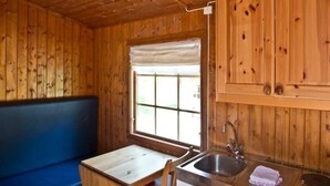 A wooden cabin interior with a wooden bench, a small table, a sink, and a window with a view. - 4 Person Holiday Park Home in Kinsarvik (Ullensvang)