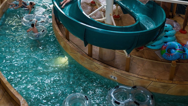 Parque acuático interior con múltiples toboganes y piscinas.