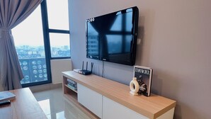 Een moderne woonkamer met een flatscreen televisie aan de muur, een houten kastje met een afstandsbediening en een tijdschrift op het kastje.