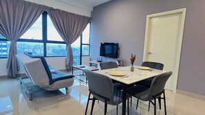 Een moderne woonkamer met een bank, een eettafel met stoelen, een flatscreen televisie en een stadsgezicht door grote ramen.