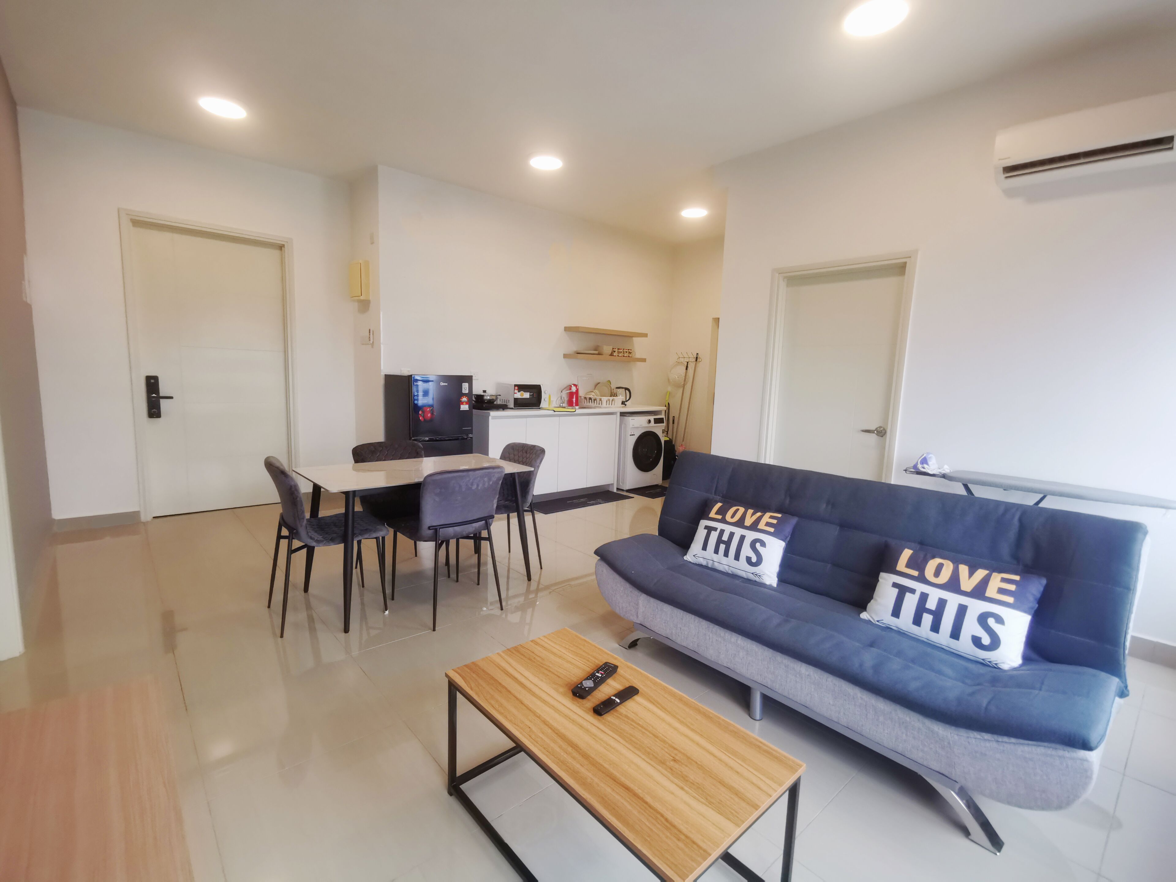 Un salon moderne comprenant un canapé, une table basse et un coin repas avec des chaises.