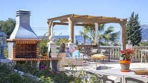 Eine Terrassengruppe mit Backofen, Sitzgelegenheiten und Blumentöpfen.