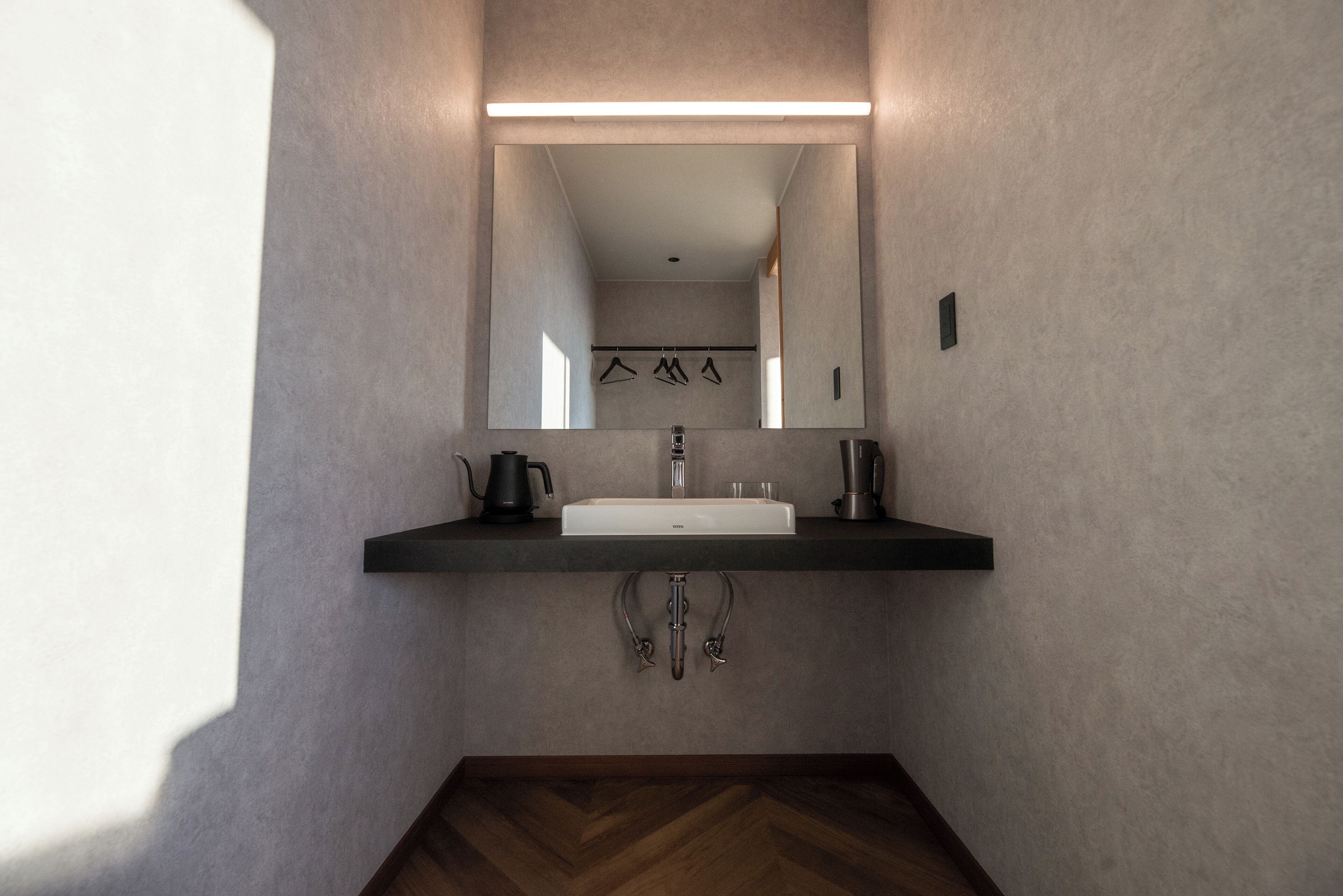 Une salle de bain moderne avec un grand miroir, un lavabo blanc et un plan de toilette noir.