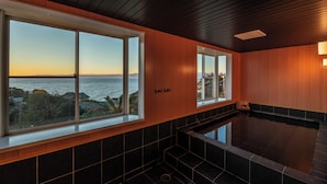A spa area with a large window overlooking the sea, a hot tub, and wooden paneling. - VACATION VILLA BLUE LAGOON (Numazu)