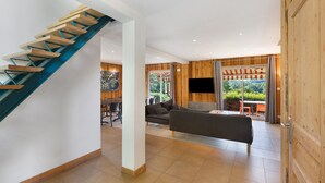 A modern living room with a wooden staircase, a sofa, and a TV.