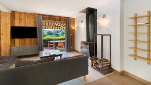 A modern living room with a sofa, TV, fireplace, and wooden shelves.