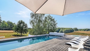 A wooden deck with a swimming pool, lounge chairs, and a large umbrella. - Modern holiday home with private pool and spa in the Périgord countryside (Angoisse)