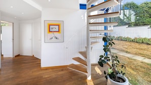 A modern interior with a wooden staircase, white walls, and a framed picture. - Modern holiday home with private pool and spa in the Périgord countryside (Angoisse)
