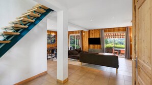 A modern interior with a wooden staircase, a sofa, and a TV. - Spacious and bright holiday home in the heart of Périgord, terrace, pool & nature (Angoisse)