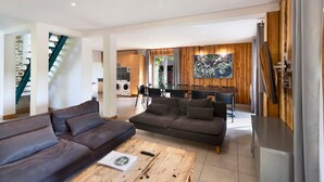 A modern living room with a sofa, coffee table, and a dining area with chairs and a table. - Spacious and bright holiday home in the heart of Périgord, terrace, pool & nature (Angoisse)