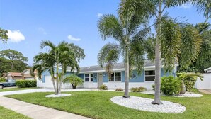 A residential house with a front lawn, palm trees, and a driveway.