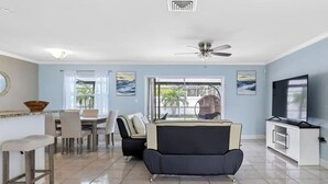 A modern living room with a sofa, dining area, and TV.