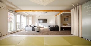 Ein modernes Hotelzimmer mit einer großen Schiebetür, einem Sofa, einem Bett und einem Fernseher an der Wand.