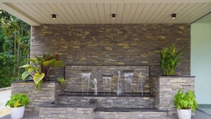 A stone water feature with multiple streams, surrounded by potted plants.
