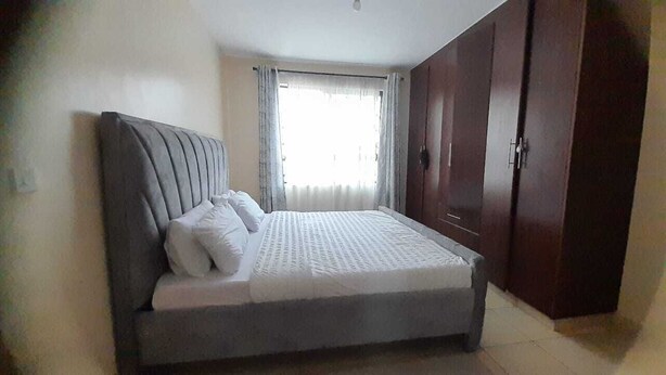 A bedroom with a bed, curtains, and a wardrobe.