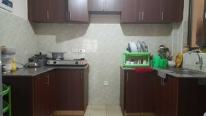 A compact kitchen with dark wooden cabinets, a gas stove, and a green dish rack.
