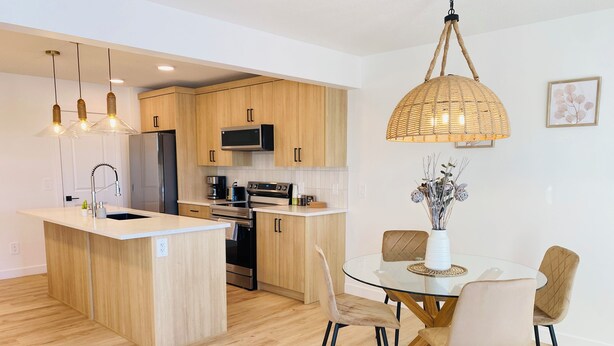 Una cocina moderna con armarios de madera, electrodomésticos de acero inoxidable y una isla central con un fregadero.
