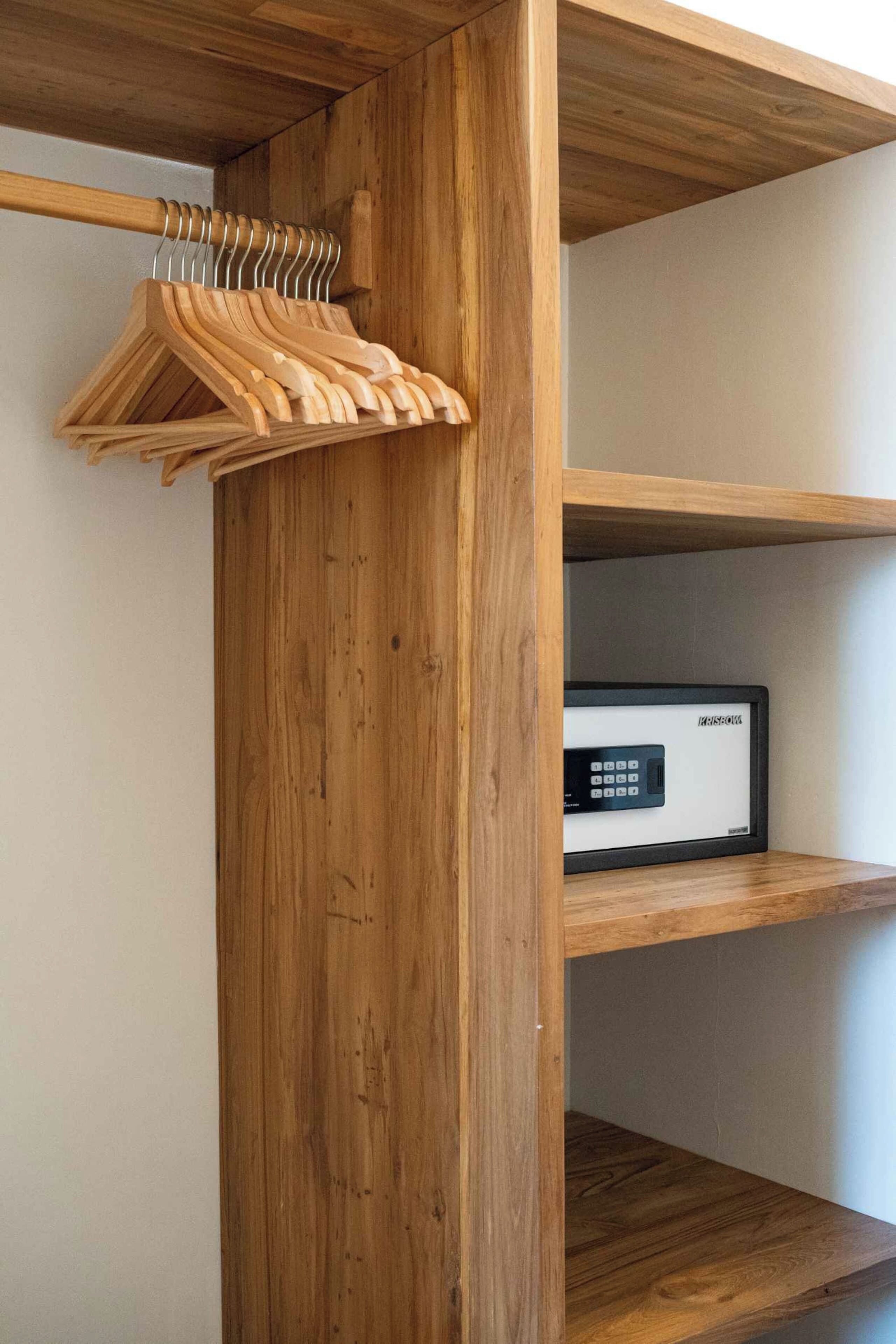 Une armoire en bois dotée d’un coffre-fort intégré et d’une tringle à vêtements en bois.