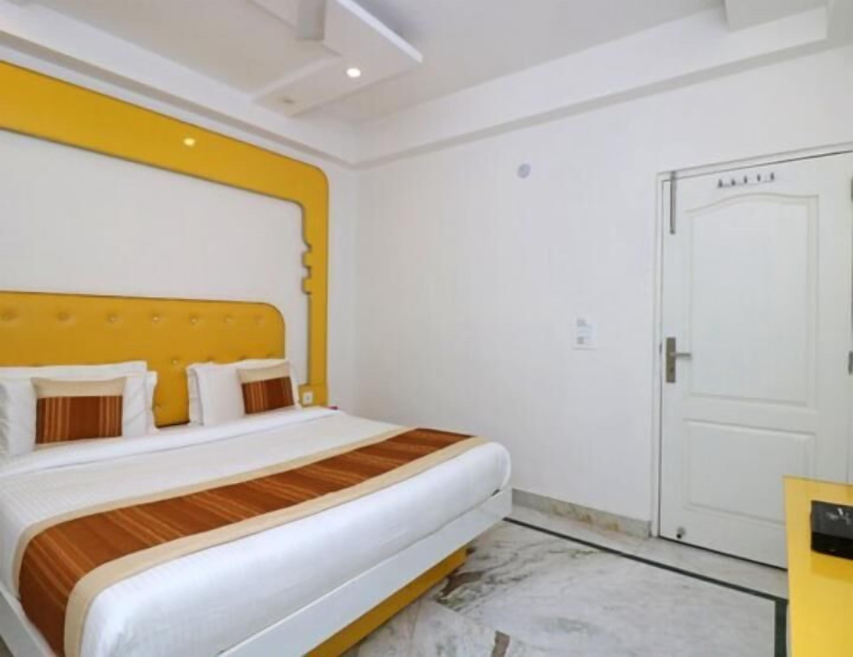 Una habitación de hotel con una cama grande, una puerta blanca y una pared de acento amarilla.