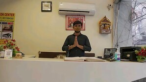A reception desk with a person standing behind it, a framed picture on the wall, and a small shrine. - Hotel Leo Continental  (New Delhi)