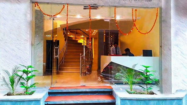 The entrance of HOTELELLO CONTINENTAL with a reception desk, staircase, and potted plants. - Hotel Leo Continental  (New Delhi)