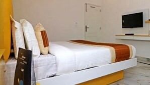A modern bedroom with a bed, a television mounted on the wall, and a door in the background. - Hotel Leo Continental  (New Delhi)