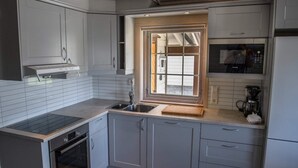 A modern kitchen with grey cabinets, a built-in oven, a sink, and a window with a view of the outside. - Spacious Holiday Home in Kinsarvik (Ullensvang)