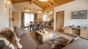 A modern living room with a sofa, a coffee table, and a dining area with chairs and a table. There is a kitchen visible in the background. - Penthouse in Wagrain Near Grafenberg Lift (Wagrain)