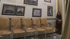Un espace d’attente agrémenté d’un lustre, de tableaux encadrés aux murs et d’un ventilateur de plafond.