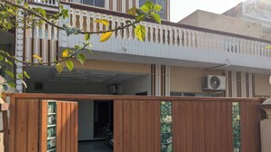 Een houten poort met decoratief paneel, leidend naar een woongebied met balkon en airconditioning.
