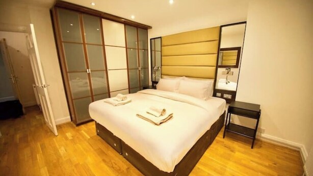 Un dormitorio con una cama grande, un armario con puertas correderas, una mesita de noche y un espejo.