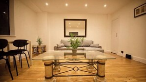 Una sala de estar moderna con una mesa de centro de vidrio, un sofá y un comedor con sillas.