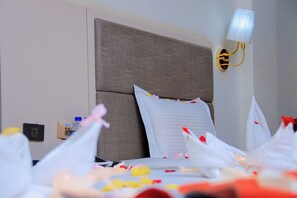 Une chambre d’hôtel avec un grand lit, une lampe fixée au mur et une prise électrique sur le mur.