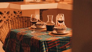 A dining table set with wine glasses, a pitcher, and bowls, covered by a patterned tablecloth. - Beach front Mawimbi Studio in stunning garden (Coast)