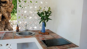 A bathroom with a sink, a blue vase with a plant, a wooden stool, and a tree trunk. - Beach front Mawimbi Studio in stunning garden (Coast)