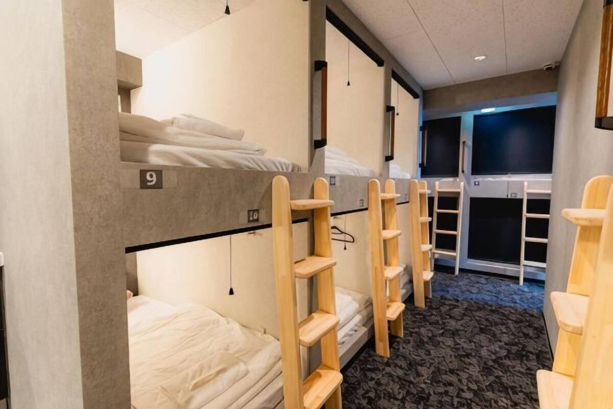 A bunk room with numbered beds, wooden shelves, and a carpeted floor.