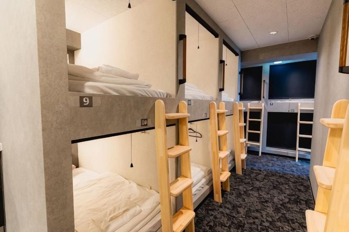 A bunk room with numbered beds, wooden shelves, and a carpeted floor.