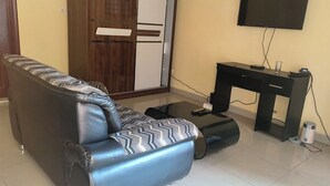 Un soggiorno con un divano in pelle, una televisione, un tavolino e un mobile.