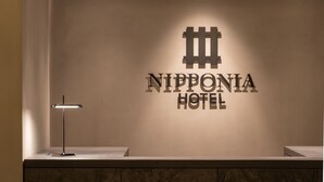 A wall with the text "NIPPONIA HOTEL" and a minimalist lamp. - NIPPONIA HOTEL Hakodate Port Town (Hakodate)
