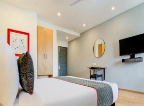 A modern hotel room with a bed, a desk, a mirror, and a TV. - Hotel Neelkanth Inn (Ahmedabad)