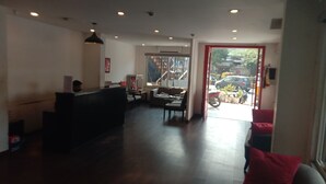 A reception area with a reception desk, seating area, and a view of the street outside. - Hotel Neelkanth Inn (Ahmedabad)