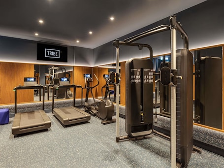 A gym with treadmills, elliptical machines, and weight machines.. TRIBE Krakow Old Town