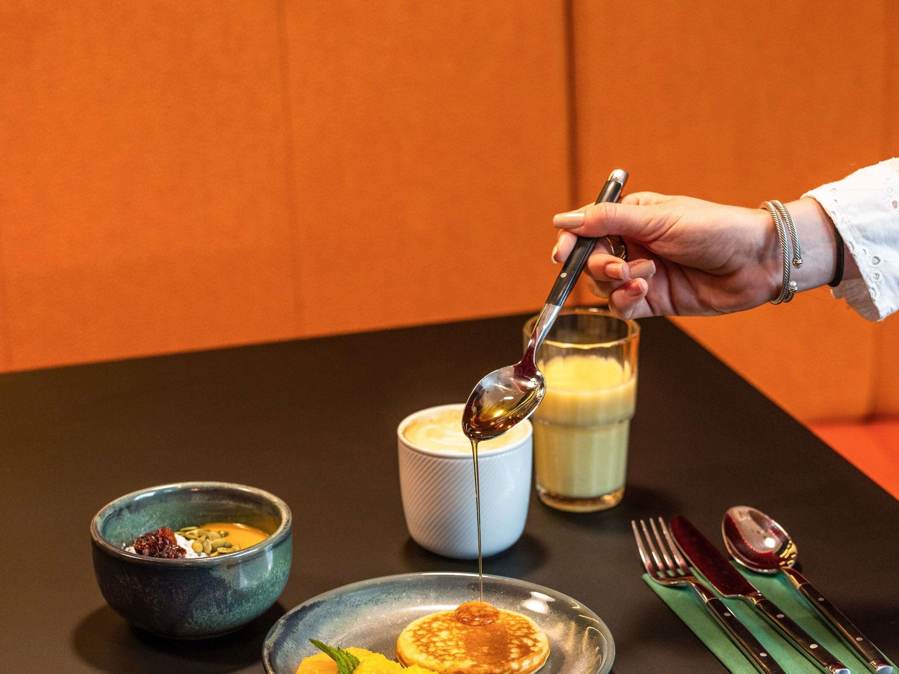 Une table à manger avec une assiette de crêpes, un bol de soupe, un verre de lait et une cuillère.